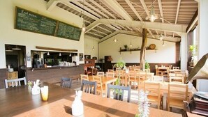 Un restaurante con mesas y sillas de madera, un menú en una pizarra y lámparas colgantes.