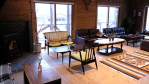 Una sala de estar acogedora con chimenea, muebles de madera y ventanas grandes.