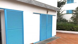 Een gebouw met blauwe luiken, een witte gevel en een pannendak.