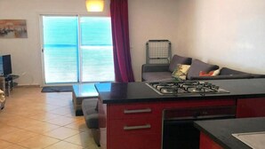 Een knus woongedeelte met een kitchenette, een bank, een eettafel en een schuifpui.