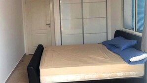 Een slaapkamer met een bed, een kledingkast en een raam met jaloezieën.