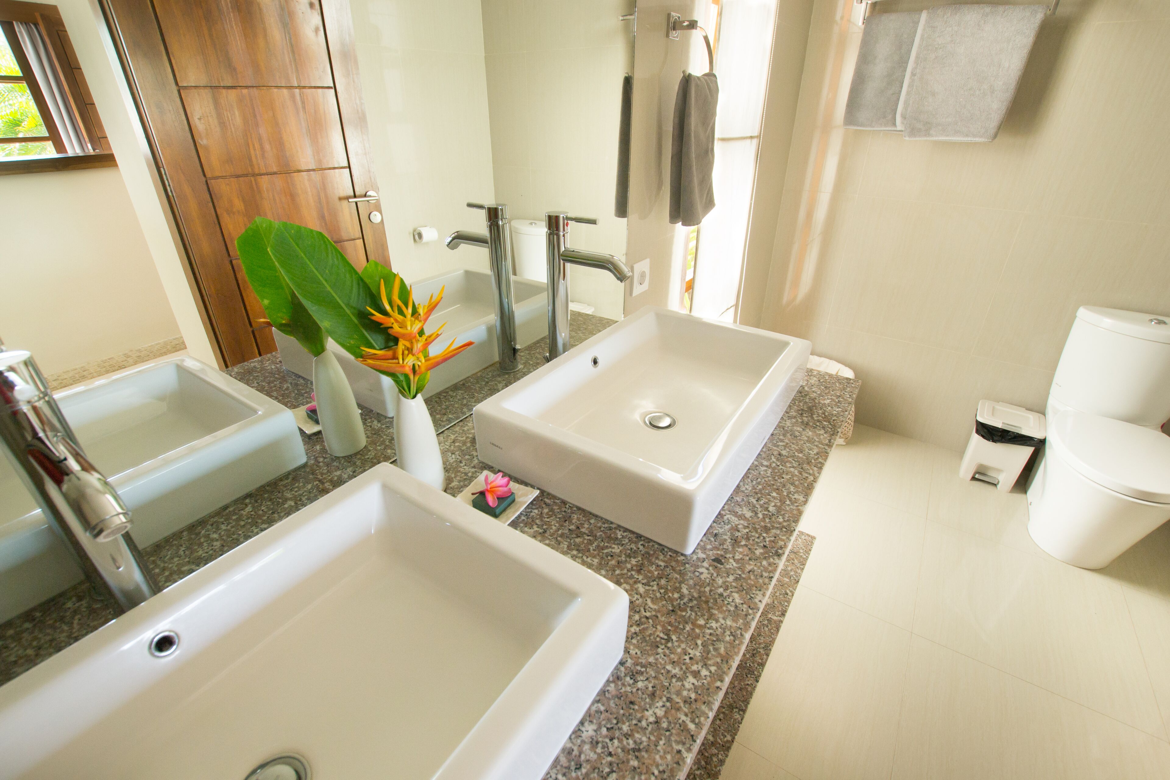 A modern bathroom with two sinks, a toilet, and a shower.