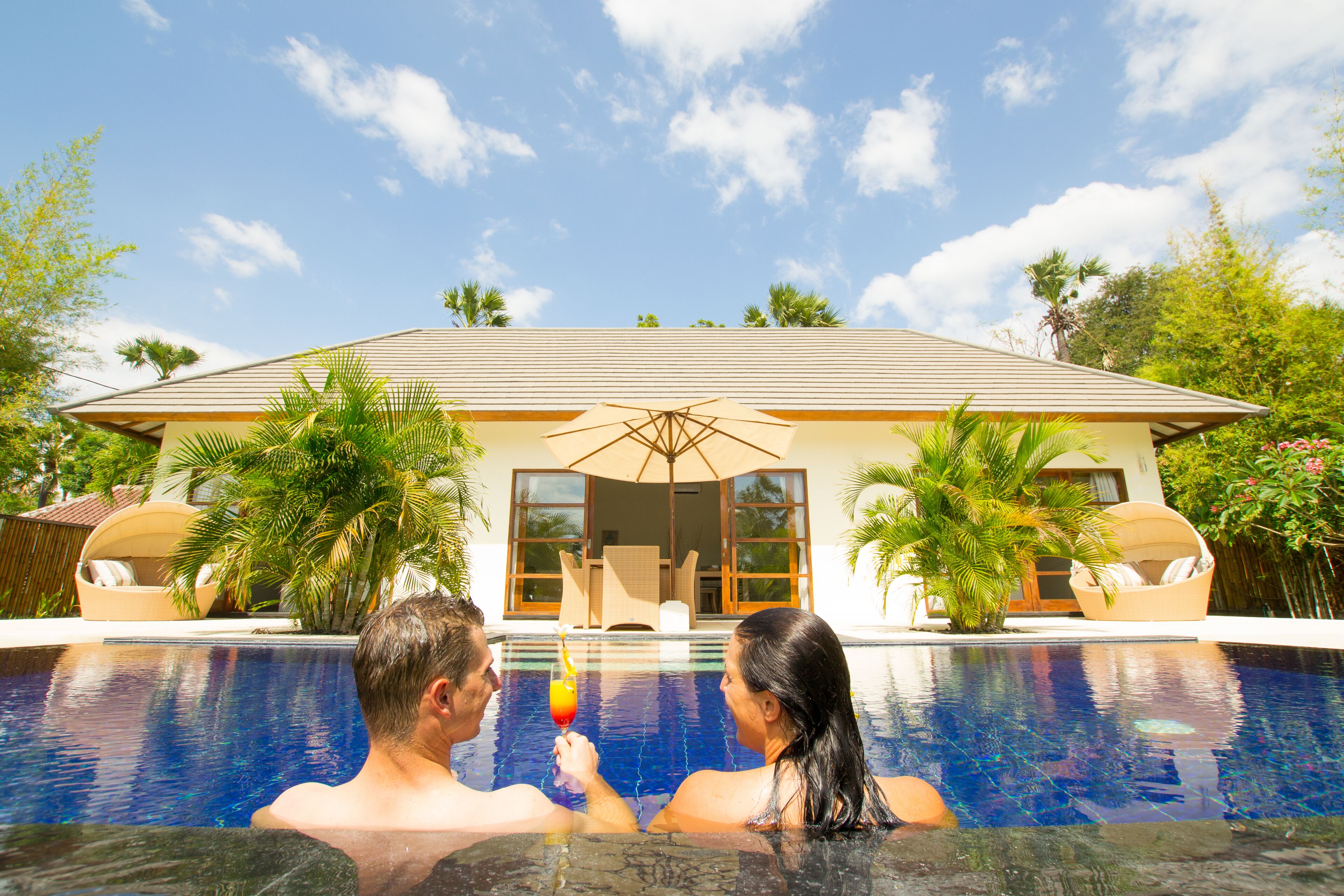 A couple in a swimming pool with a house in the background.