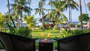 A tropical resort view with a thatched-roof pavilion, palm trees, and a pool area. - Kubu Indah Dive & Spa Resort (Kubu)