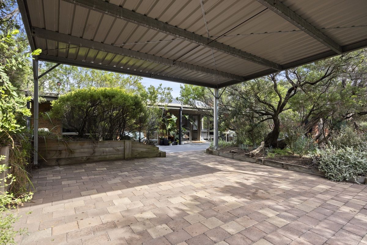 A covered outdoor area with a brick pathway leading to a gazebo.