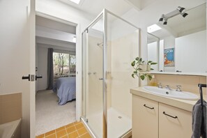 Un baño con ducha, lavabo y espejo.