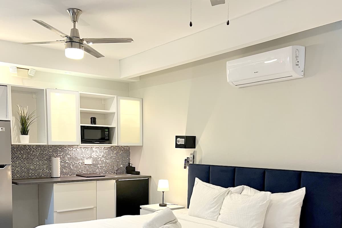 Une chambre d’hôtel moderne dotée d’un grand lit, d’un bureau intégré, d’un four à micro-ondes et d’un ventilateur de plafond.