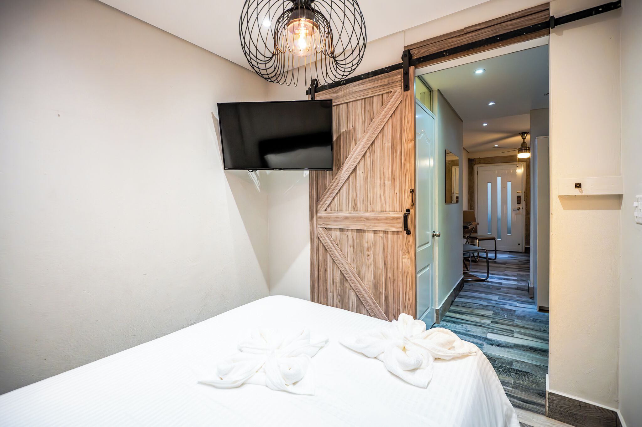 Een hotelkamer met een bed, een aan de muur bevestigde televisie en een houten deur.