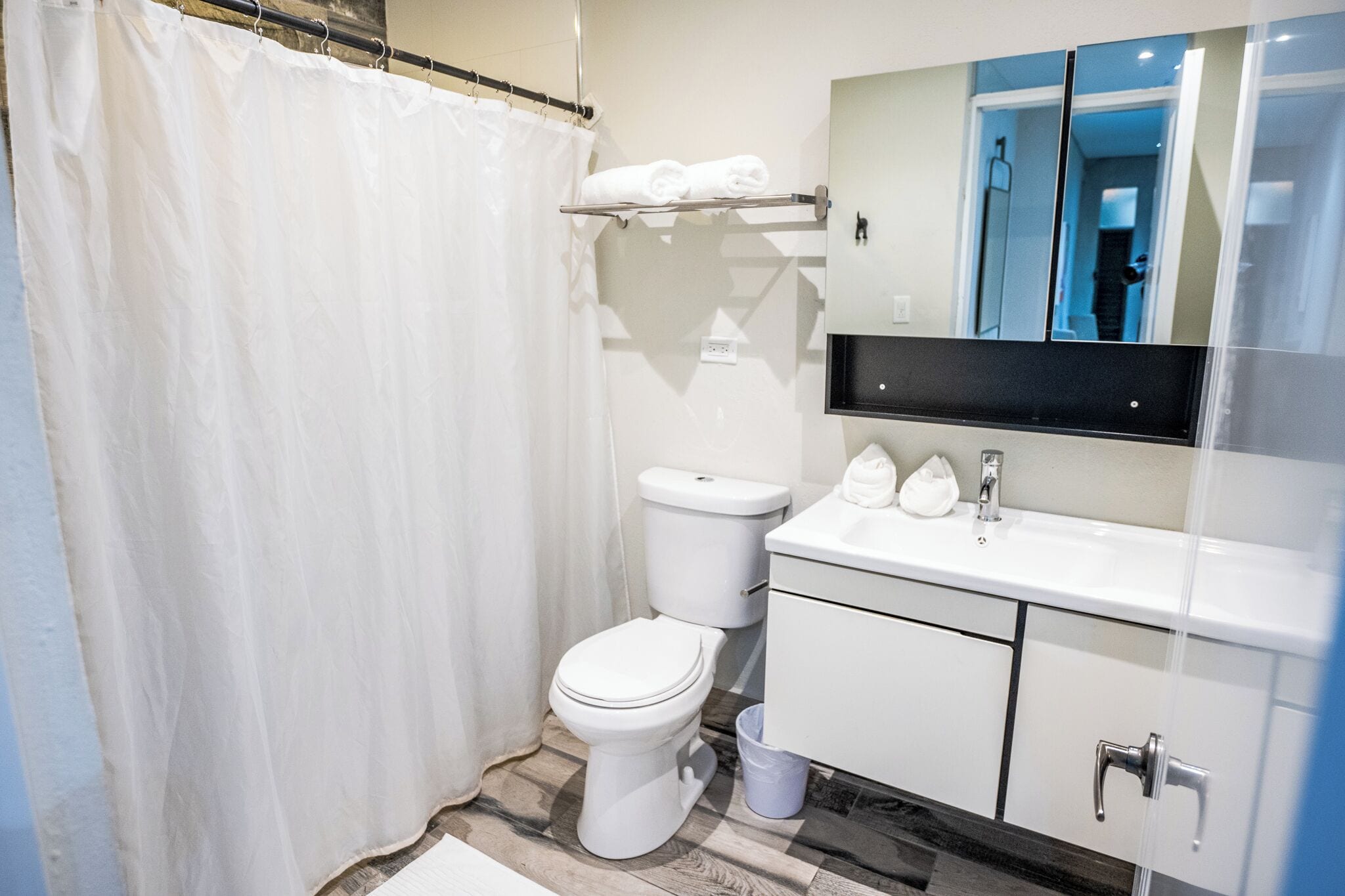 Un baño con inodoro, lavamanos, espejo y cortina de ducha.