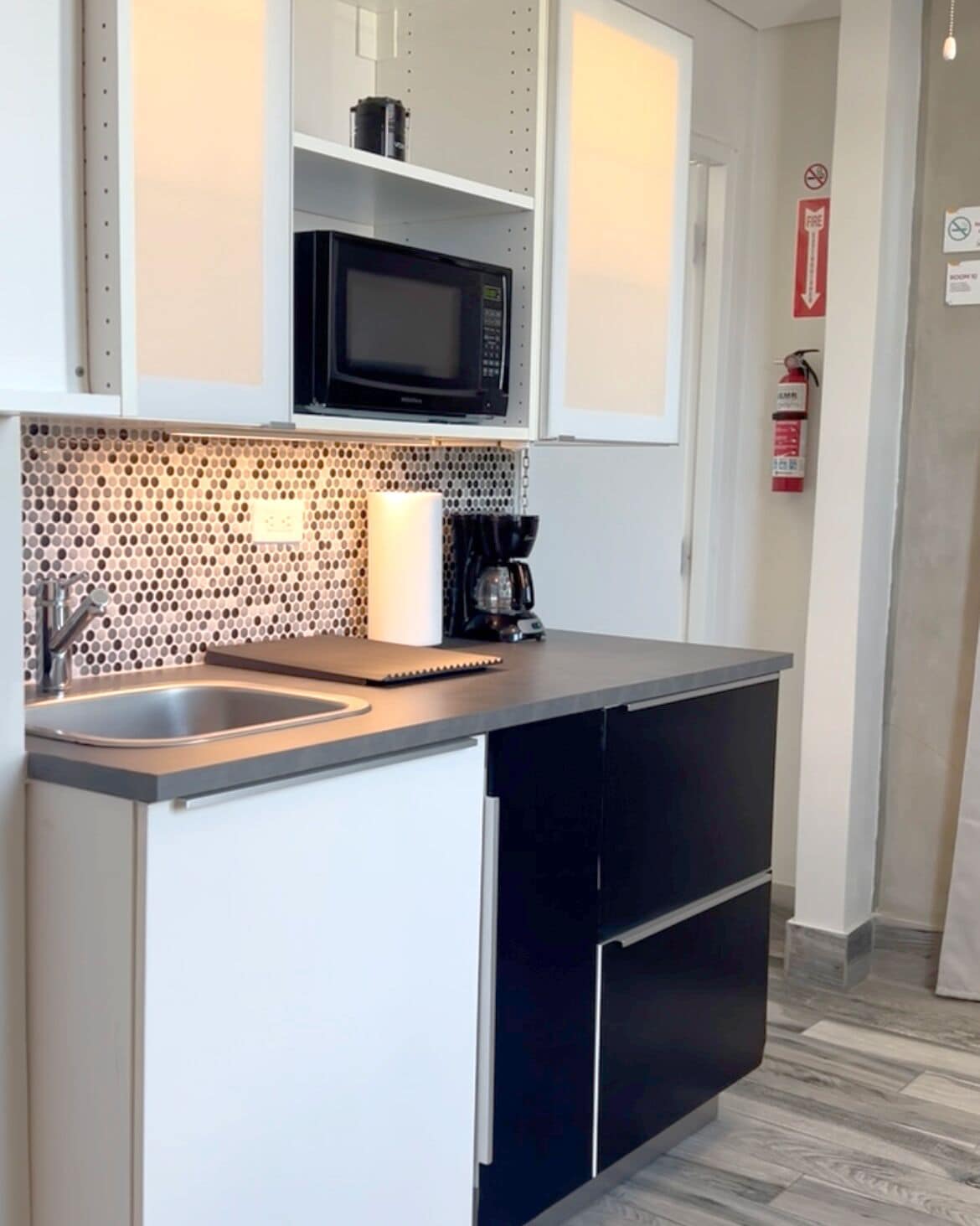 A compact kitchen with a microwave, coffee maker, and a sink.