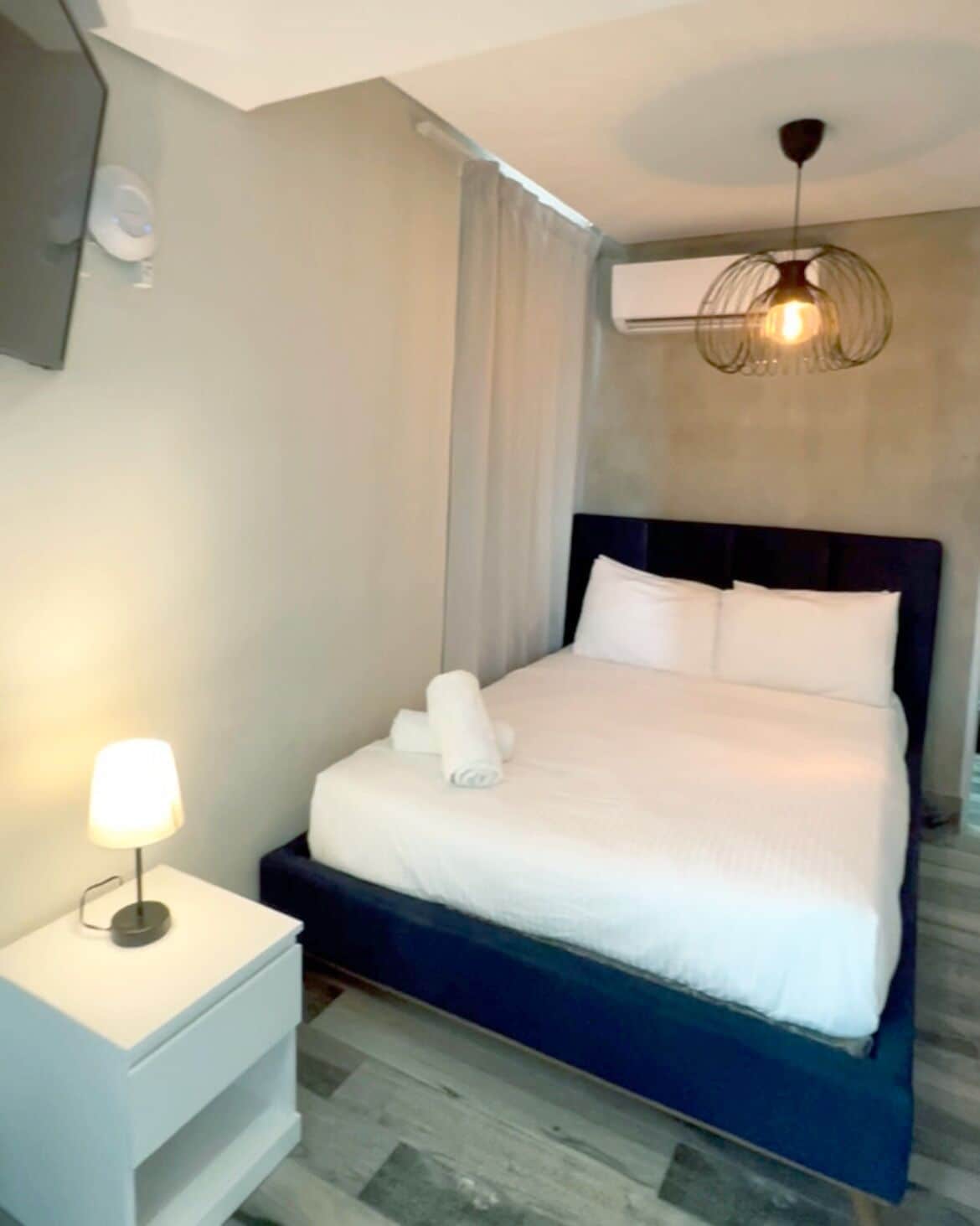 Een moderne hotelkamer met een groot bed, een nachtkastje met een lamp en een plafondlamp.