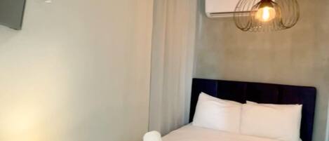 Een moderne hotelkamer met een groot bed, een nachtkastje met een lamp en een plafondlamp.