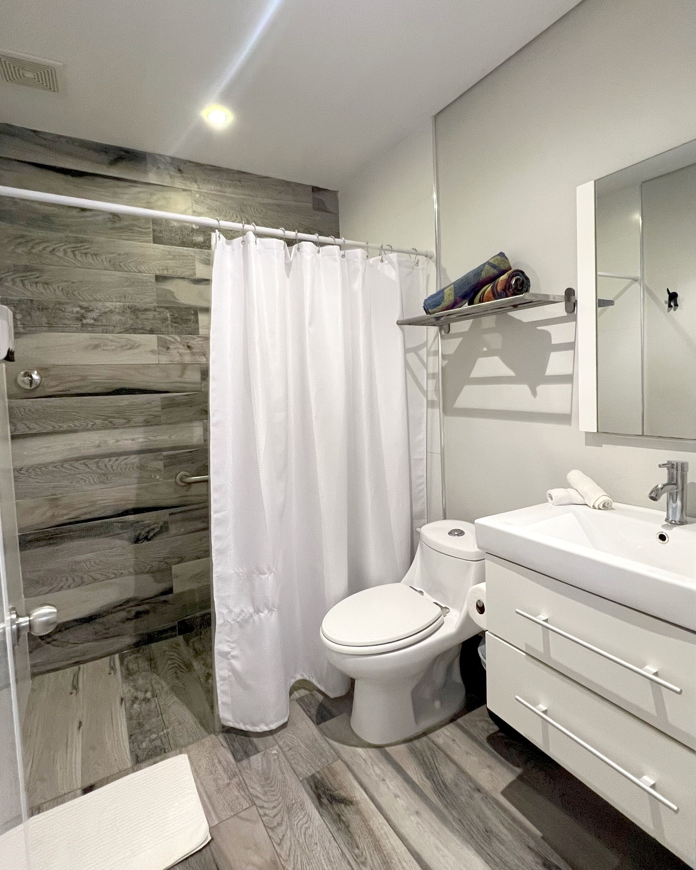 A bathroom with a shower curtain, toilet, and a sink with a mirror.
