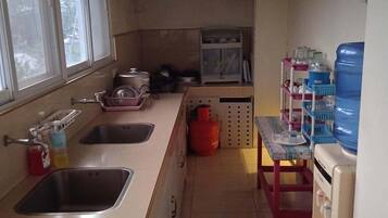 A kitchen with two sinks, a water dispenser, a gas cylinder, and a microwave.