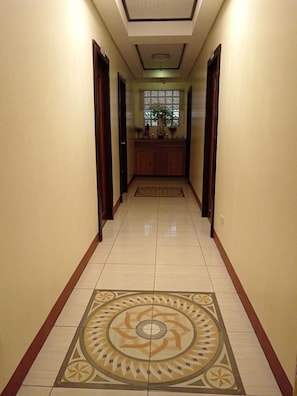 Un couloir avec un sol Ă motifs, un comptoir dâaccueil et des portes de chaque cĂŽtĂ©.