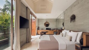 A modern bedroom with a large bed, a TV, and a kitchen area in the background. - Astera Villa Seminyak by Ini Vie Hospitality (Legian)