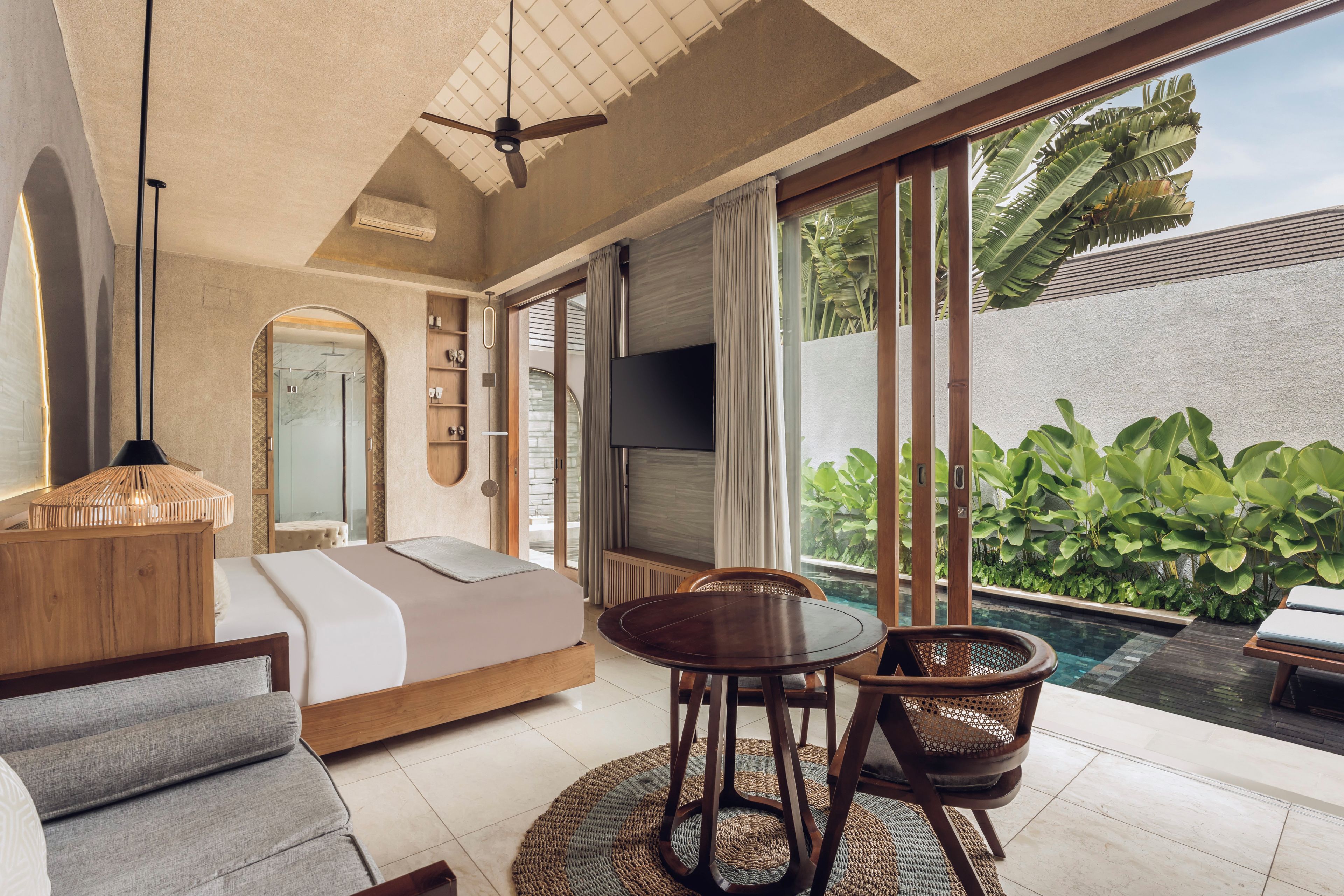 A modern bedroom with a bed, a TV, and a view of a pool.
