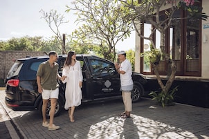 Une voiture noire est garée devant un bâtiment sur lequel on peut lire l’inscription « ASTERA VILLA SEMINYAK ».