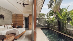 A modern bedroom with a large bed, a dining area, and a pool area with tropical plants. - Astera Villa Seminyak by Ini Vie Hospitality (Legian)
