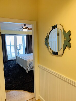 A bedroom with a bed, a ceiling fan, a window with curtains, and a door leading to a balcony.