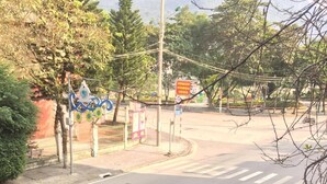 A street view with a pedestrian crossing, a fence with a gate, and a signboard. - Ha Giang Discovery Hostel (Ha Giang 1)