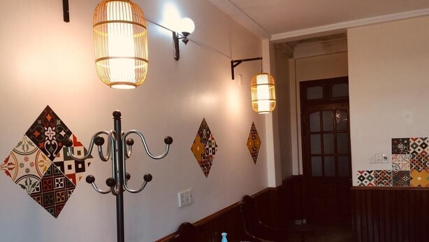 A hotel lobby with patterned wall tiles, a candelabra, and a seating area. - Ha Giang Discovery Hostel (Ha Giang 1)