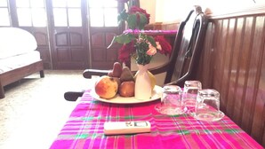 A dining table with a plaid tablecloth, a plate of bread, a vase with flowers, and a remote control. - Ha Giang Discovery Hostel (Ha Giang 1)