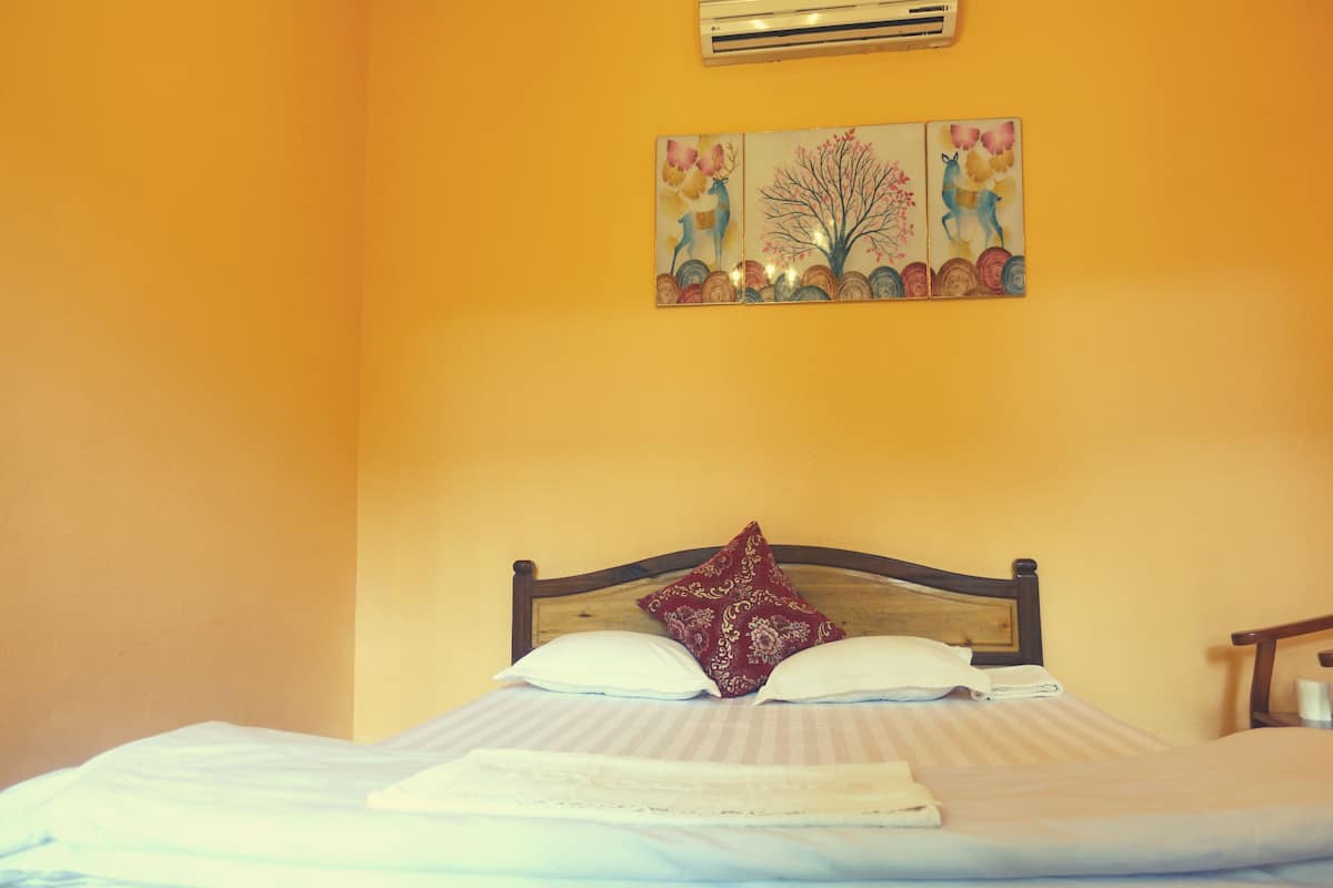 A bed with a wooden headboard, white bedding, and a red patterned pillow.