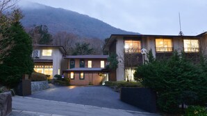A two-story building with a flat roof, a balcony on the upper floor, and a well-lit entrance. - HESTA Hakone (Hakone)