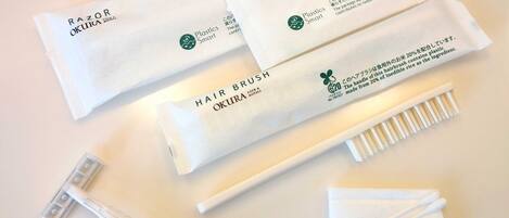 Toiletries including razors, hairbrushes, and cotton pads, all branded with 'OKURA Hotels'.