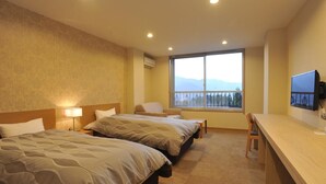 A hotel room with two beds, a desk, a chair, a TV, and a large window with a mountain view. - HESTA Hakone (Hakone)