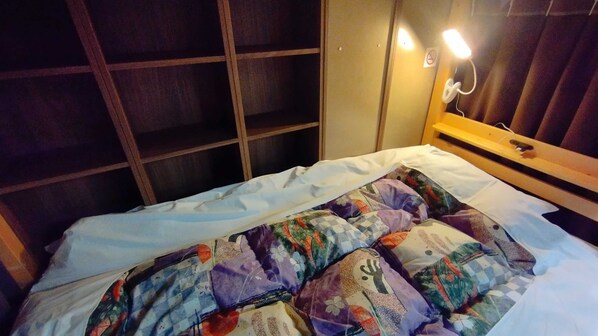 Un lit avec une couverture colorée, une tête de lit en bois et une lampe de chevet.