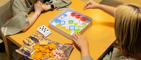 A person playing a board game with colorful circular pieces on a table.