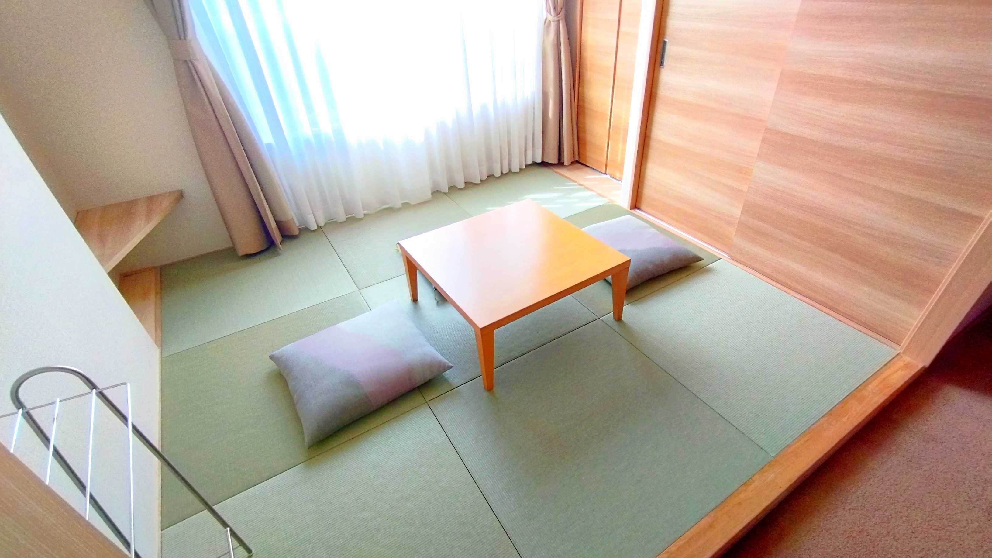 A room with tatami mat flooring, a low wooden table, and cushions.