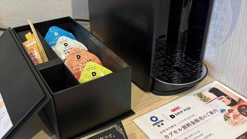 A drip coffee maker with a black box containing coffee pods and a card with Japanese text.