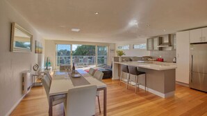 A modern kitchen with a central island, a dining area with a large window, and a view of the outdoors.