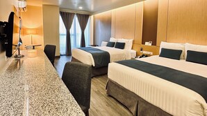 Ein Hotelzimmer mit zwei Betten, einem Schreibtisch und einem Fernseher.