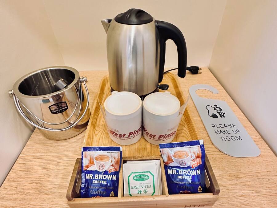 A coffee station with a kettle, two mugs, a tray with coffee packets, and a sign indicating the room.