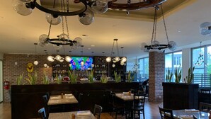 Ein Restaurant mit Barbereich, Holzboden und einem Fernsehbildschirm.