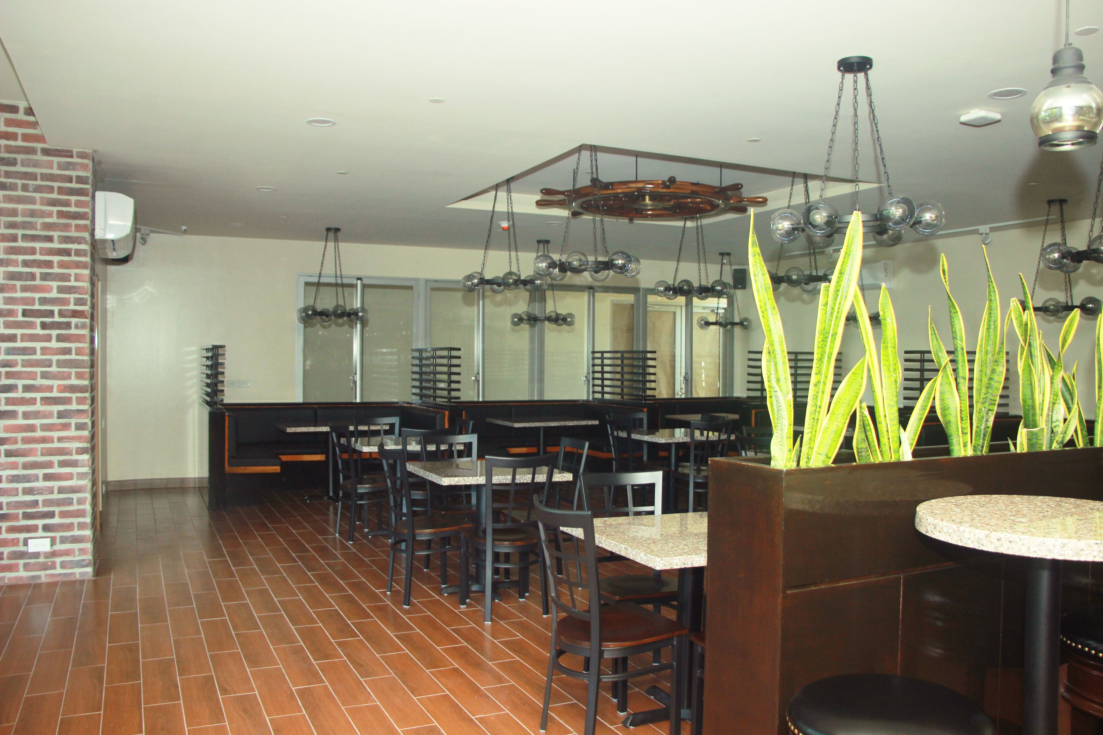 A restaurant with brick walls, tiled floors, and multiple tables and chairs.