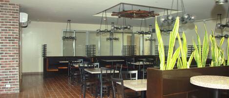 Un restaurante con paredes de ladrillo, pisos de baldosas y varias mesas y sillas.