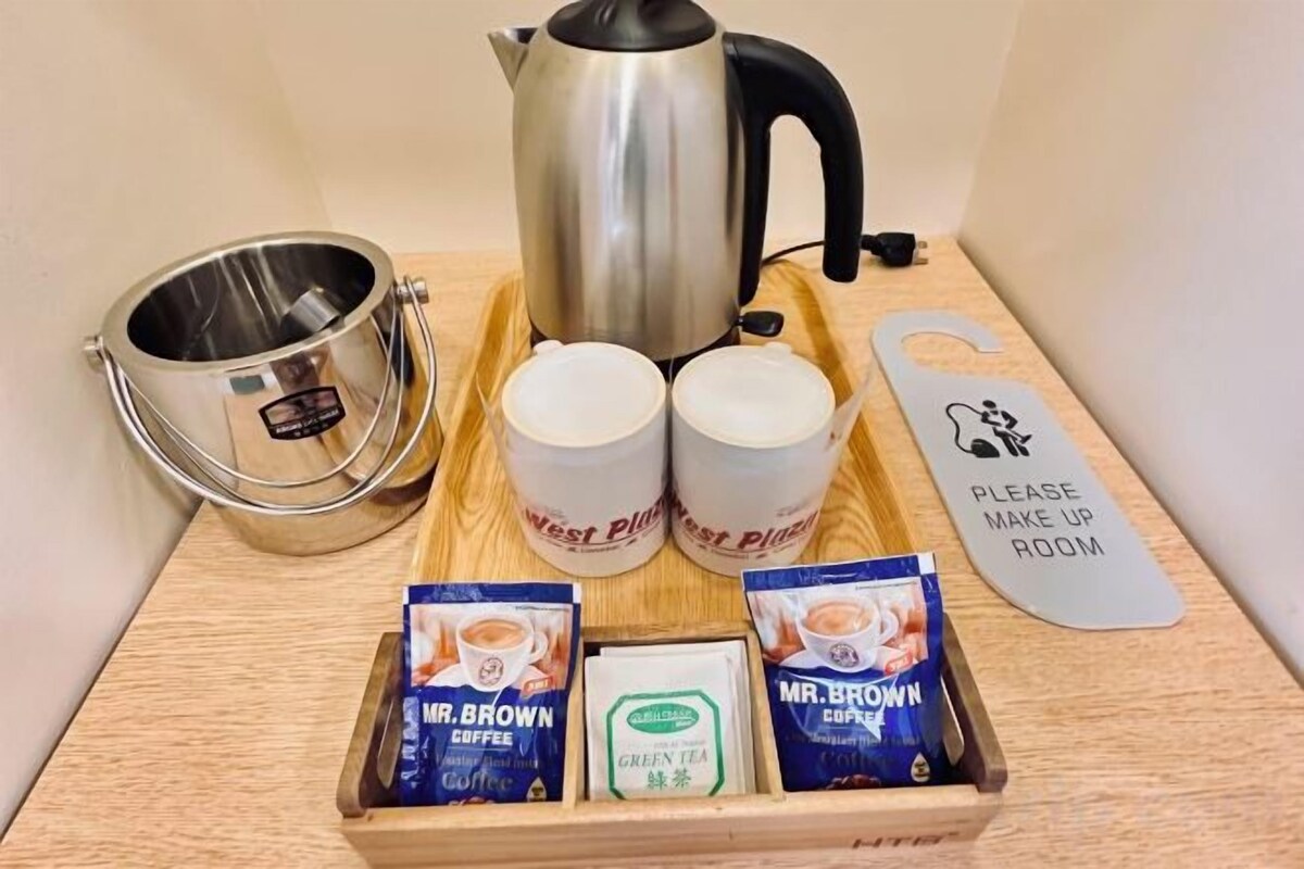 Una disposición para preparar café con una tetera, tazas y sobres de café sobre una bandeja.