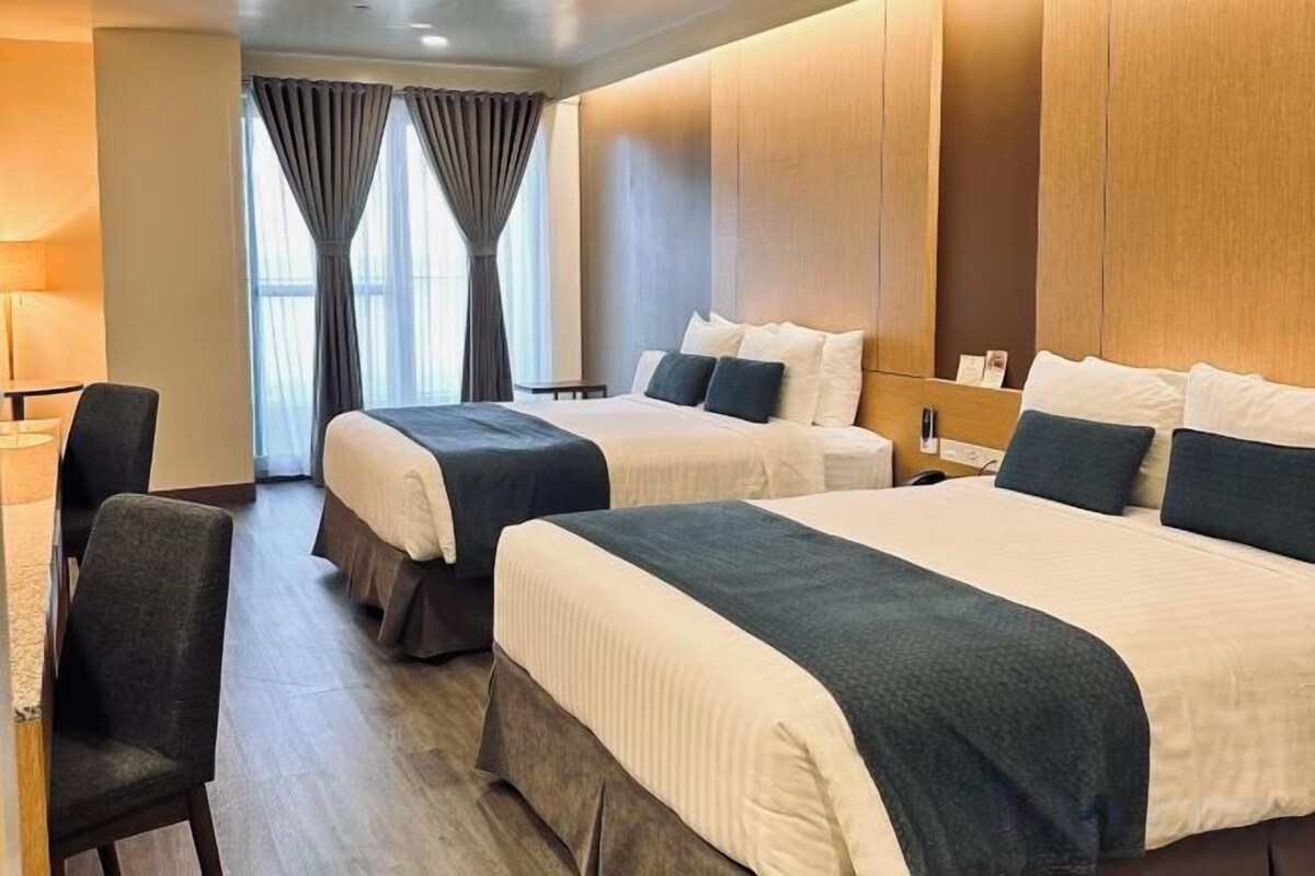 Habitación de hotel con dos camas, un escritorio y una silla.