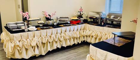 Een buffetopstelling met diverse gerechten en een decoratieve tafelkleed.