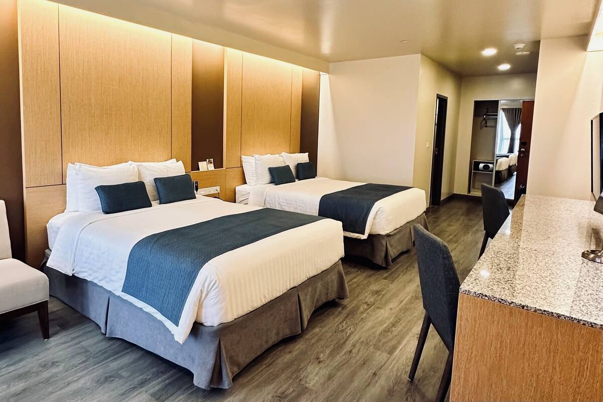 Habitación de hotel con dos camas, un escritorio y una silla.