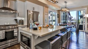 A modern kitchen with stainless steel appliances, a large island with bar seating, and a view of the outside.