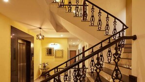 Escadaria moderna com grades metálicas decoradas, piso lustroso e iluminação interna acolhedora.
