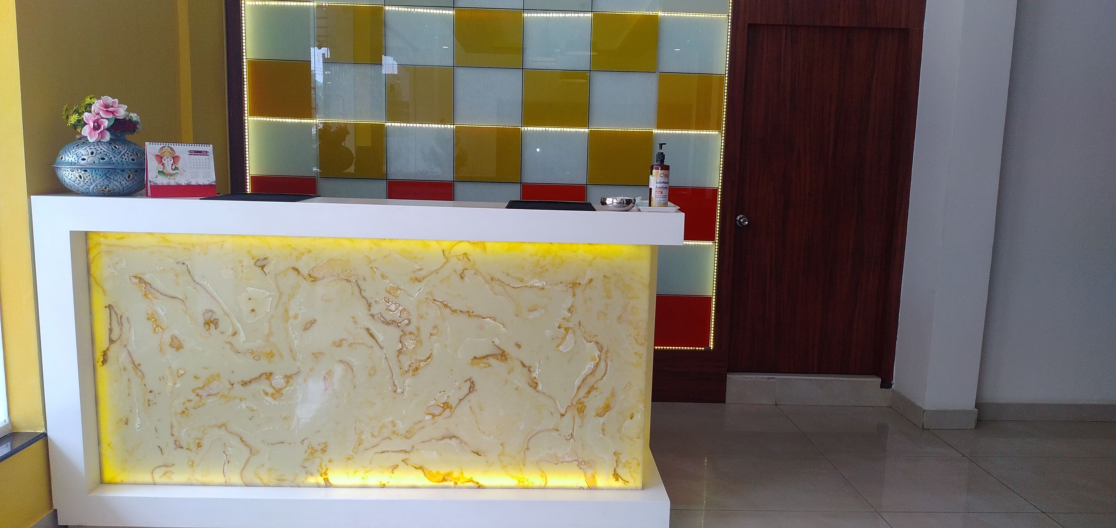 A reception desk with a marble-like design and a colorful glass partition in the background.