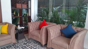 Uma sala de estar com dois sofás marrons, uma mesa pequena e uma estante decorativa.