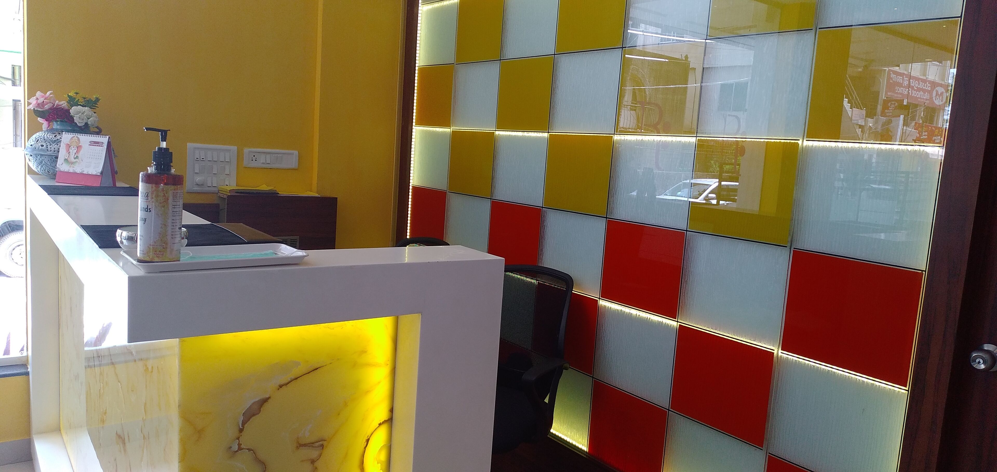 A reception desk with a calendar, a bottle, and a chair.